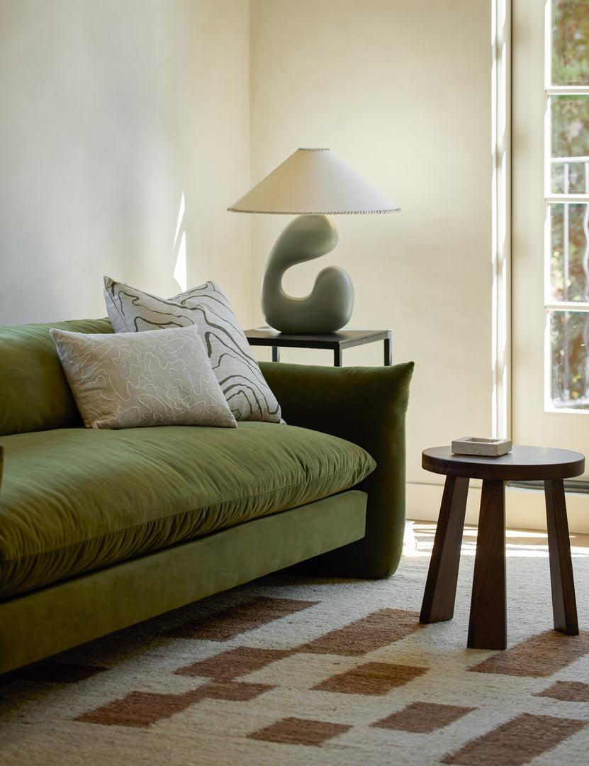 Organic table lamp placed on a wooden side table in a contemporary residential living room creating warm ambient lighting.