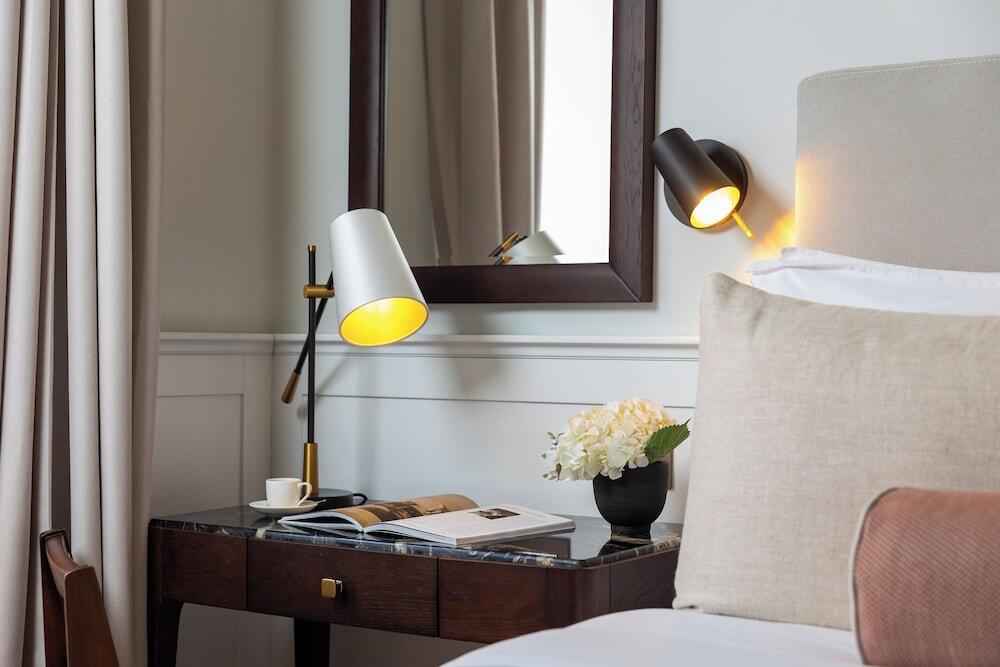 Reading table lamp positioned beside a bed in a luxury hotel guest room providing comfortable focused illumination for reading.