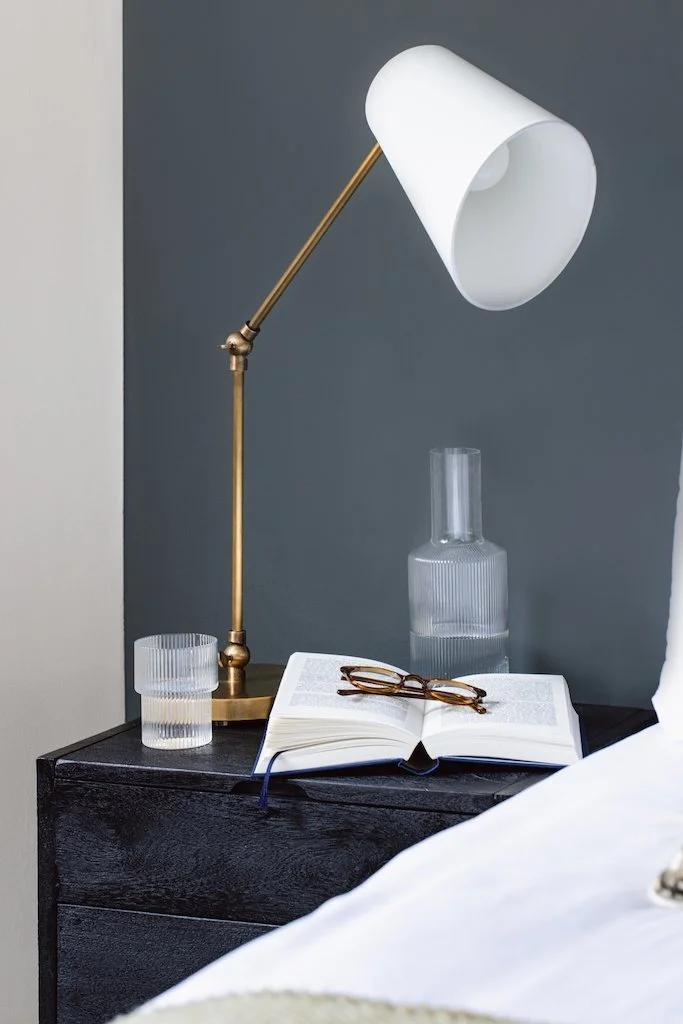 Reading table lamp positioned beside a bed in a luxury hotel guest room providing comfortable focused illumination for reading.