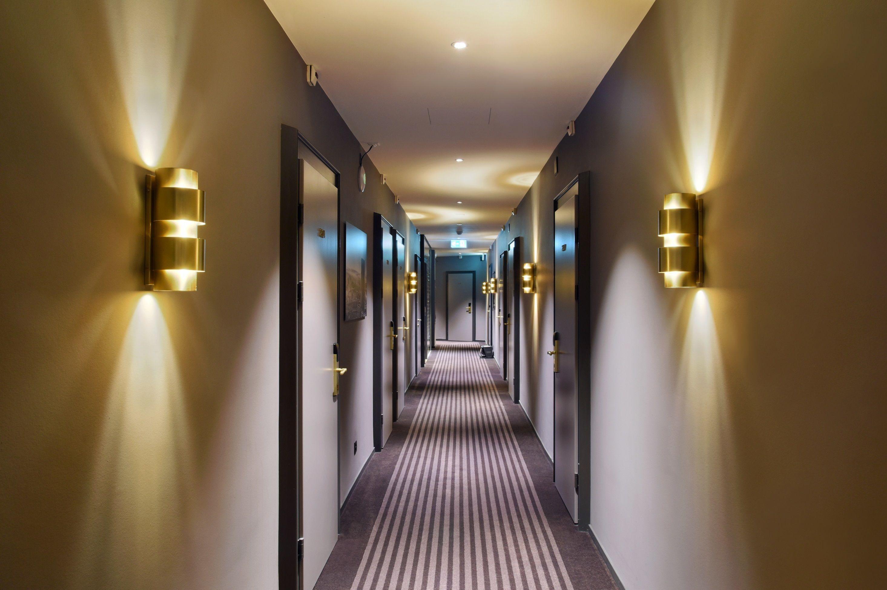 Contemporary wall lamp installed in a luxury hotel interior with sophisticated architectural styling.