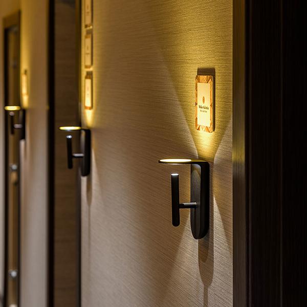 Contemporary wall lamp installed in a luxury hotel interior with sophisticated architectural styling.