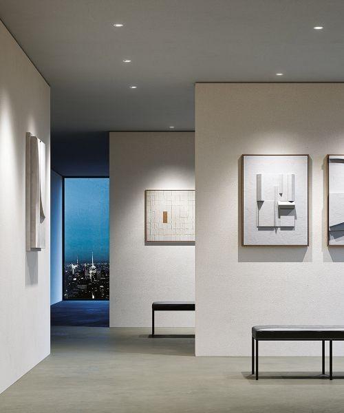 Wall washer recessed downlights providing uniform illumination on a vertical gallery wall.