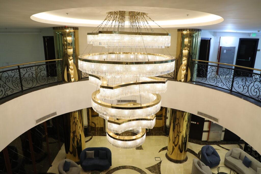 Tiered chandelier installed in a luxury hotel atrium with dramatic architectural lighting.