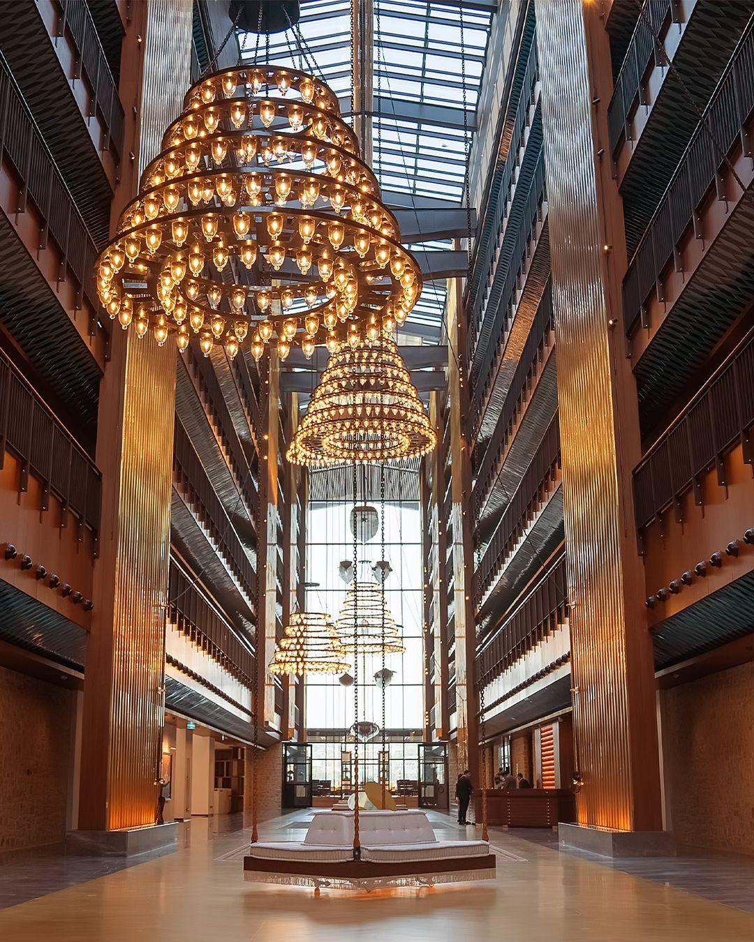 Tiered chandelier installed in a luxury hotel atrium with dramatic architectural lighting.