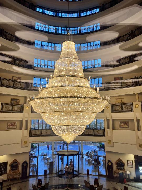 Tiered chandelier installed in a luxury hotel atrium with dramatic architectural lighting.