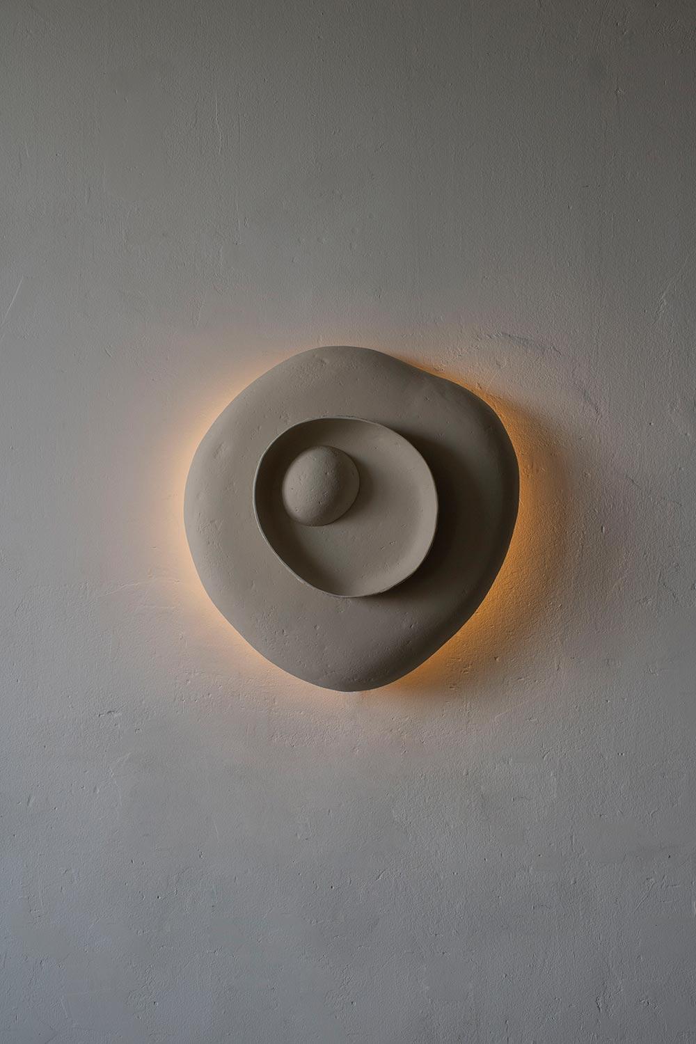 Front view of an organic wall lamp with soft curves and refined architectural detailing.