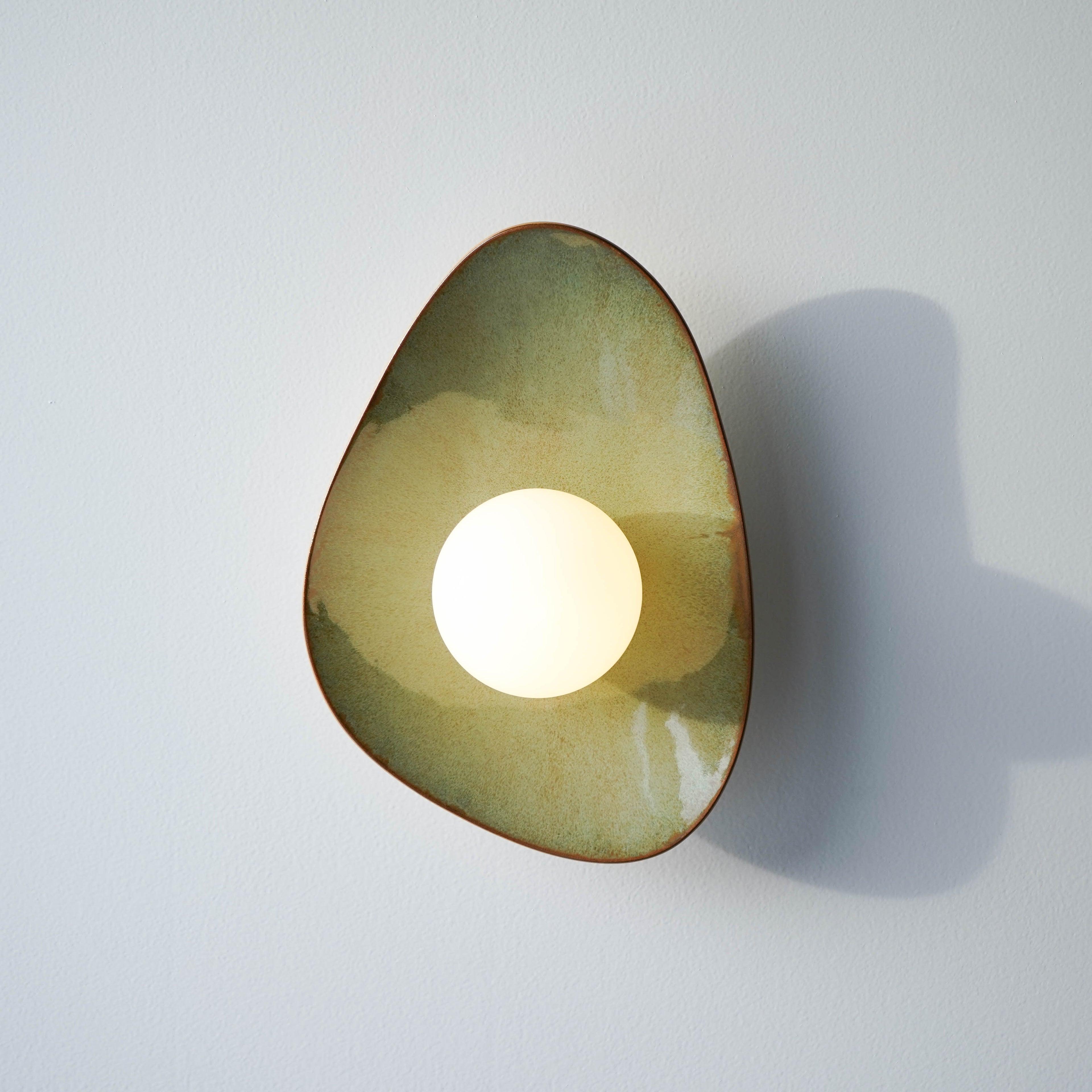 Front view of an organic wall lamp with soft curves and refined architectural detailing.