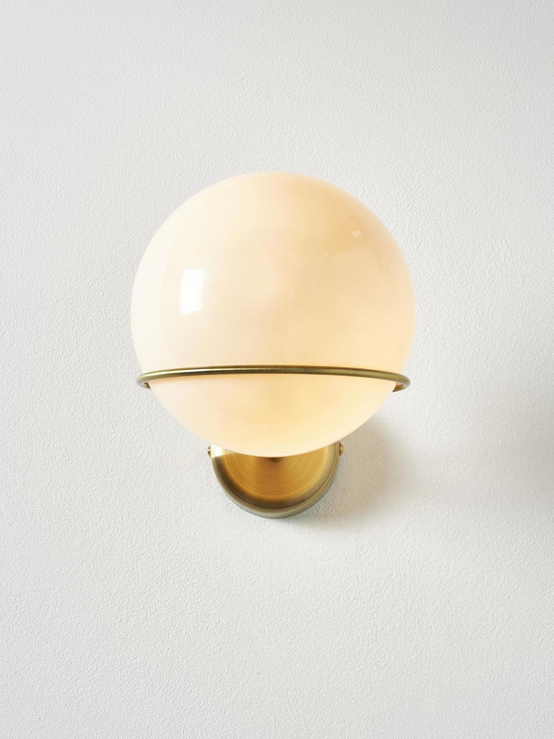 Front view of a contemporary globe wall lamp featuring opal glass and refined metal detailing.
