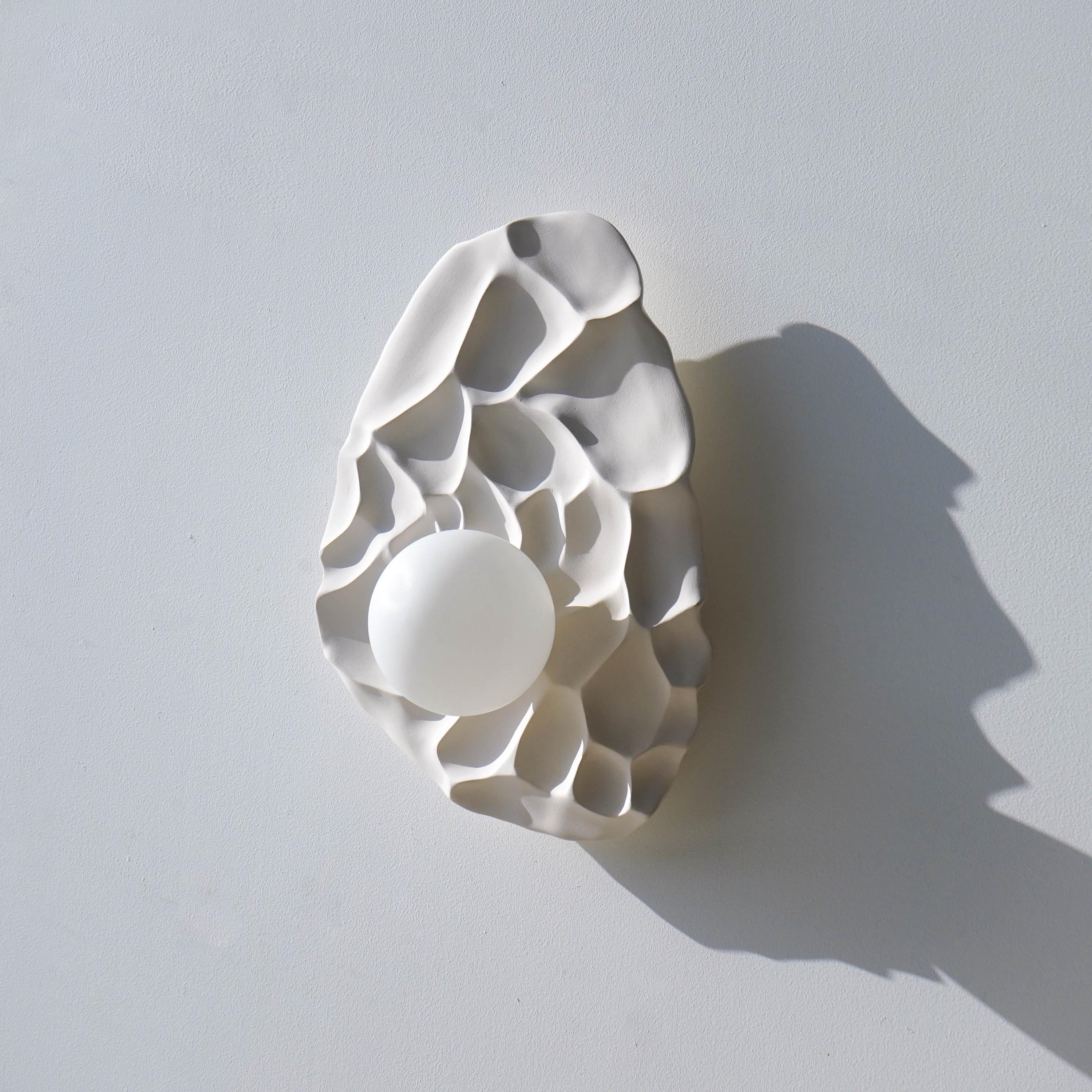 Front view of a sculptural wall lamp combining premium materials with contemporary design.