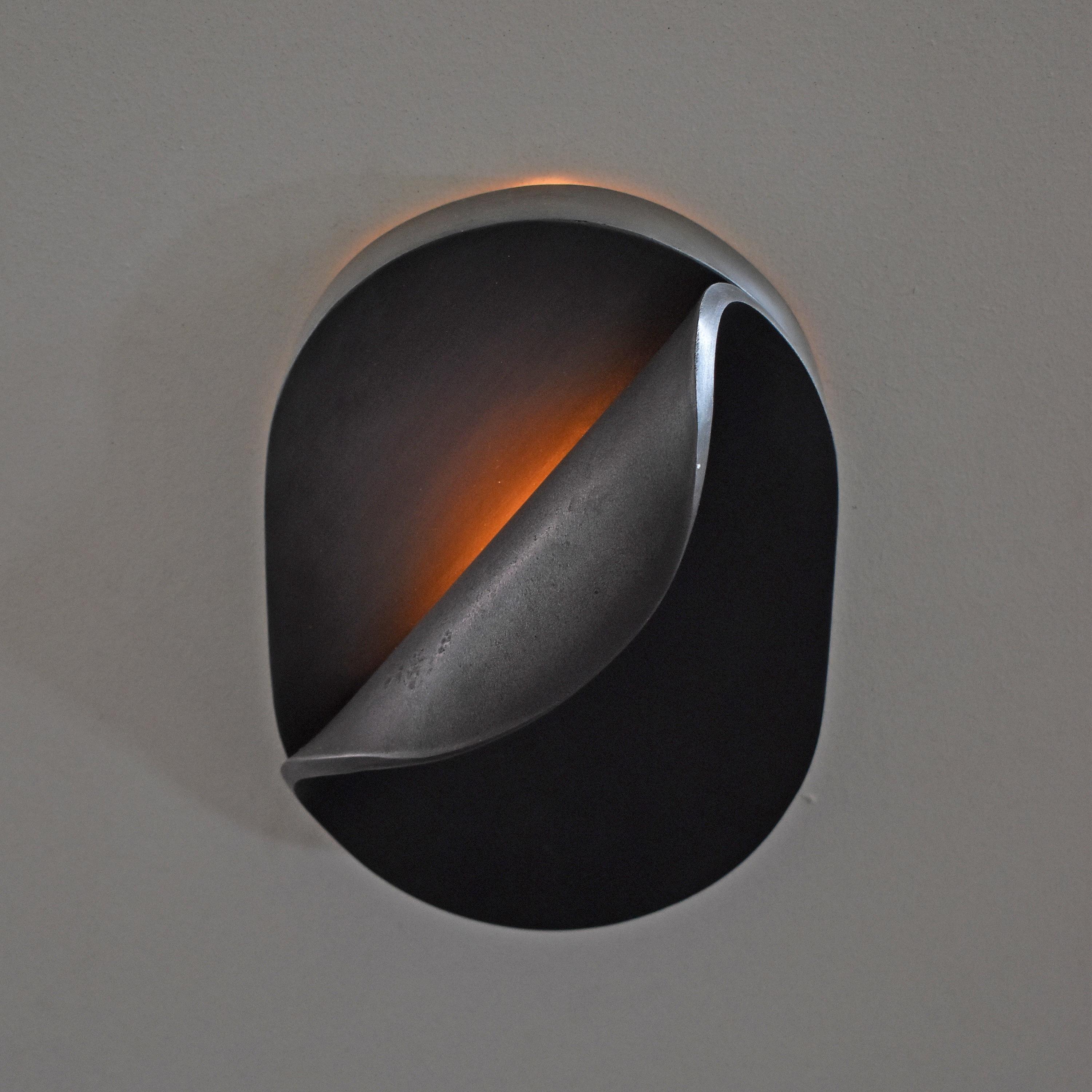 Front view of a sculptural wall lamp combining premium materials with contemporary design.