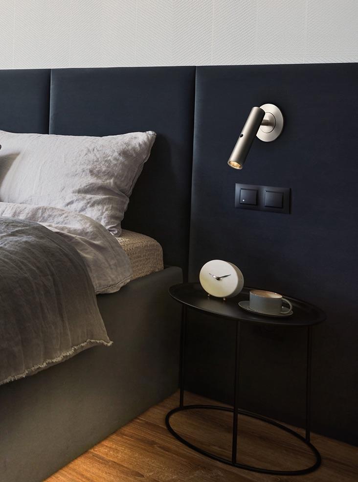 Reading wall lamp installed beside a luxury hotel bed providing comfortable task illumination.