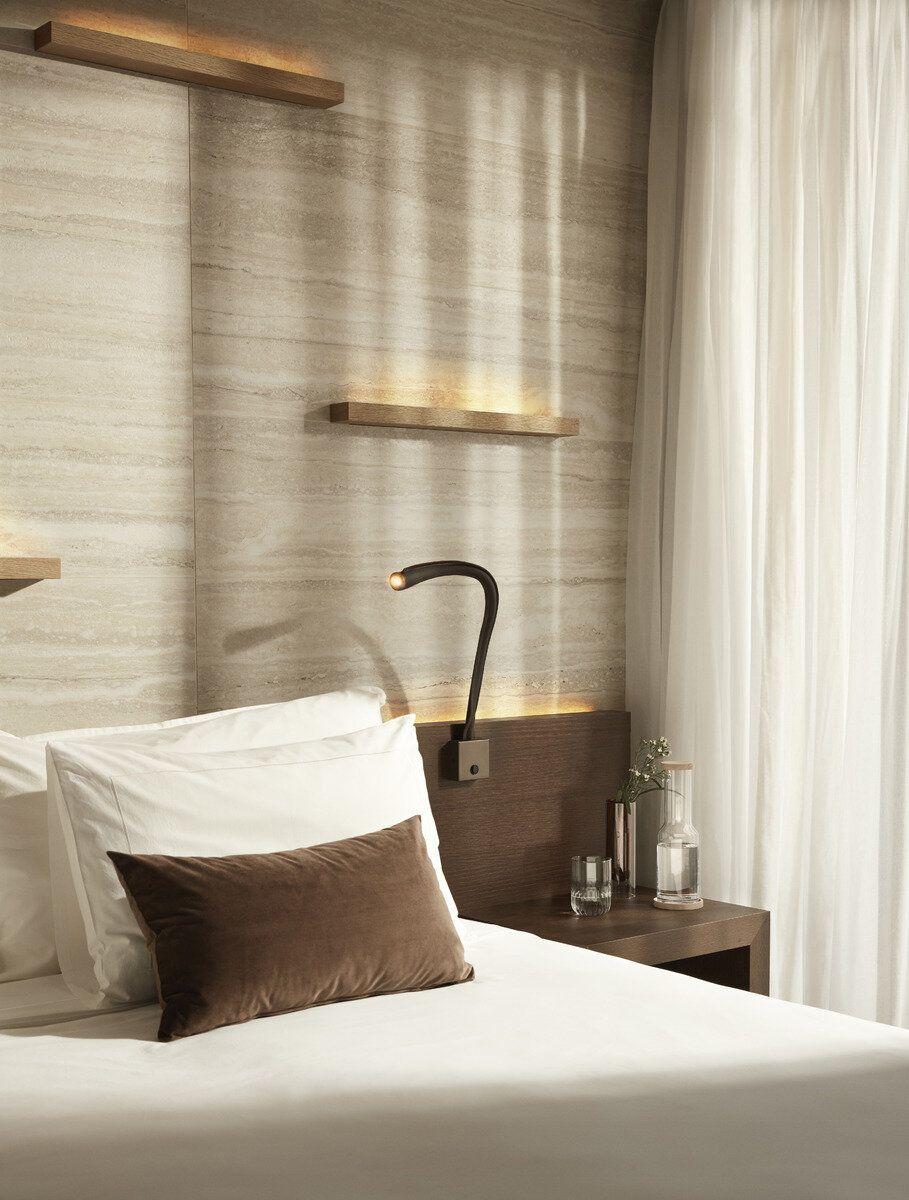 Reading wall lamp installed beside a luxury hotel bed providing comfortable task illumination.