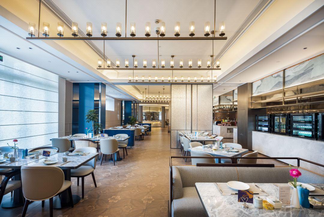 Minimal chandelier installed above a contemporary dining area in a premium architectural interior.
