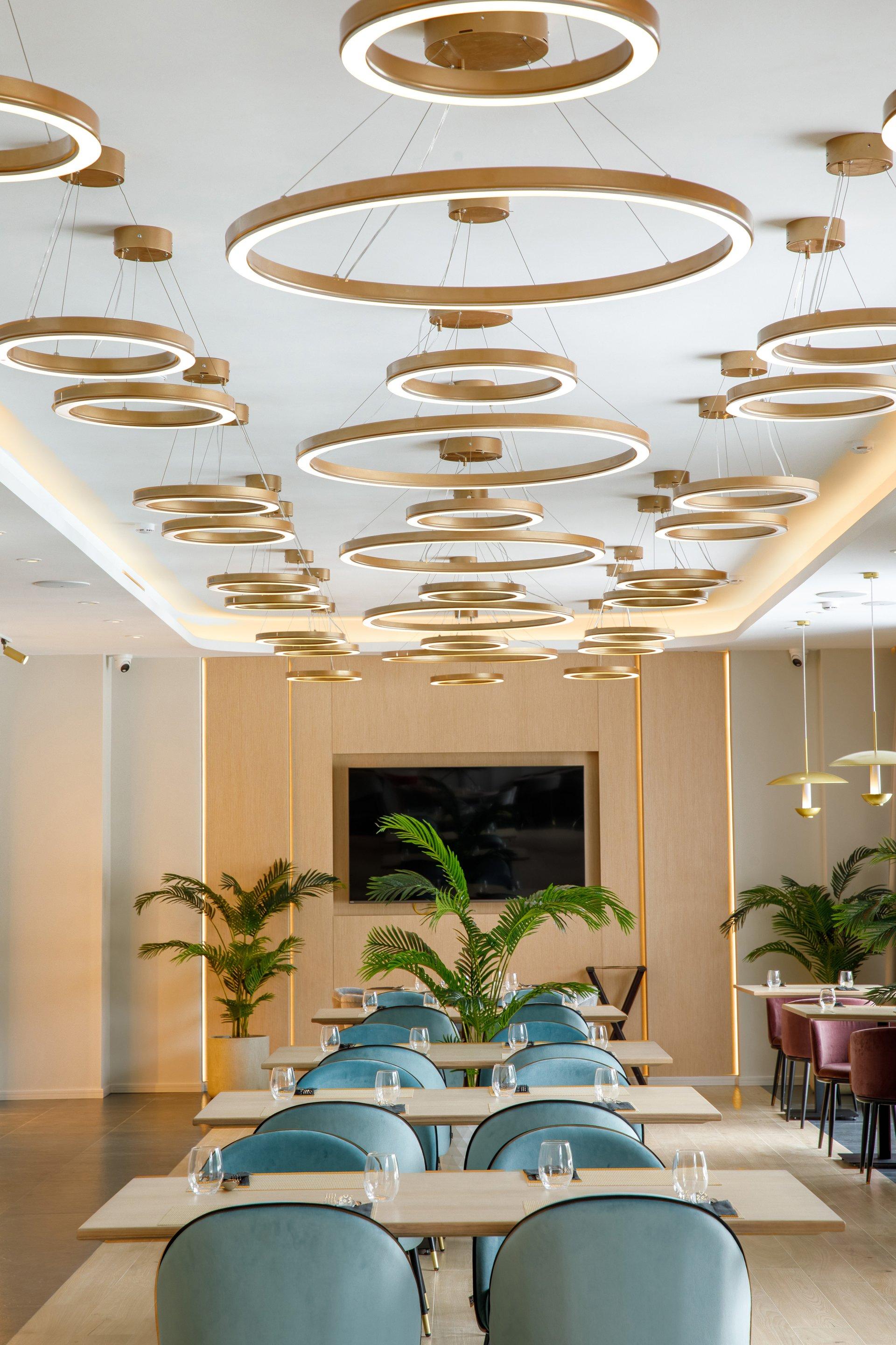 Minimal chandelier installed above a contemporary dining area in a premium architectural interior.